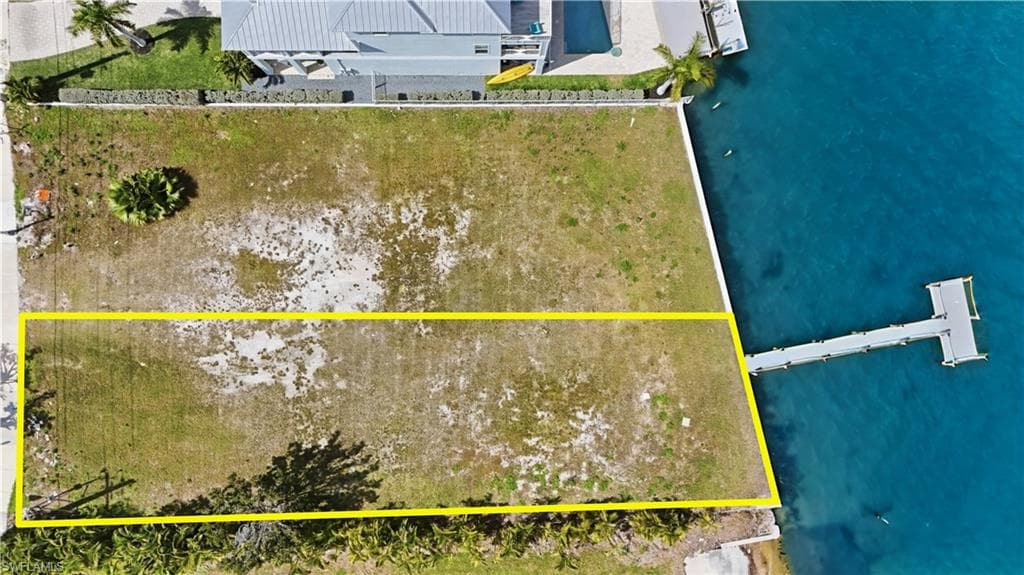 Aerial view of property and surrounding area with a nearby body of water and property parcel outlined - Virtually Edited Image