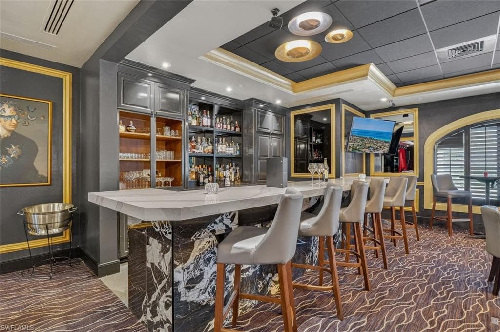 Bar with gray cabinets, ornamental molding, and recessed lighting