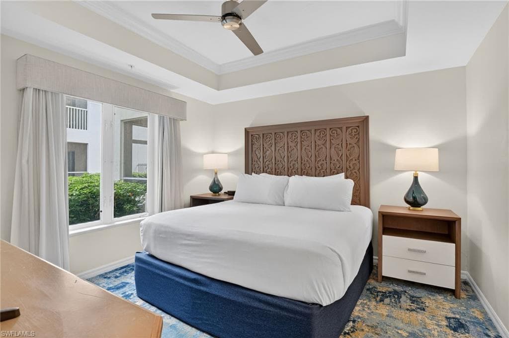 Bedroom with crown molding, a tray ceiling, and a ceiling fan