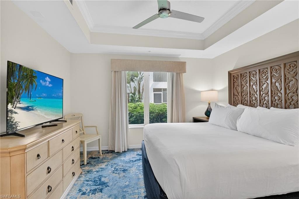 Bedroom with crown molding, a ceiling fan, a tray ceiling, and carpet flooring