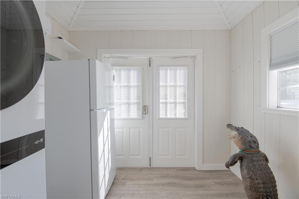 Entryway featuring wood finished floors, stacked washing machine and dryer, and wooden walls