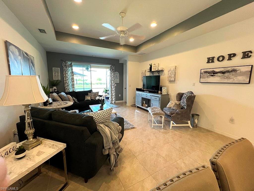 Living area featuring ceiling fan, light tile patterned flooring, a raised ceiling, and recessed lighting