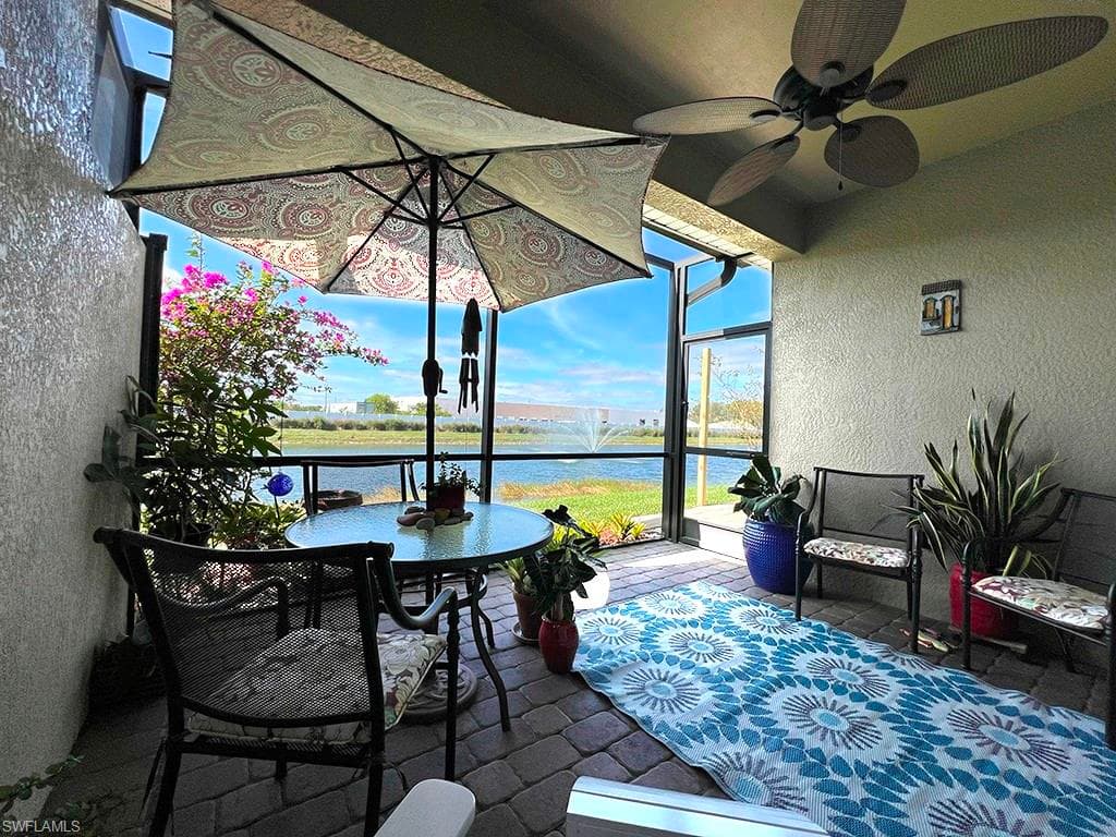 View of patio / terrace featuring a sunroom, glass enclosure, a water view, and a ceiling fan