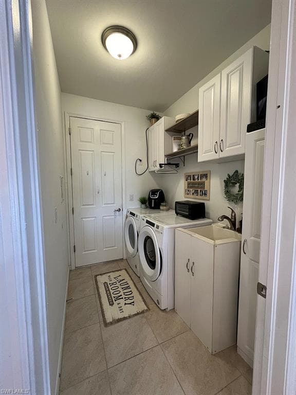 Laundry area featuring cabinet space, light tile patterned floors, and washer and dryer