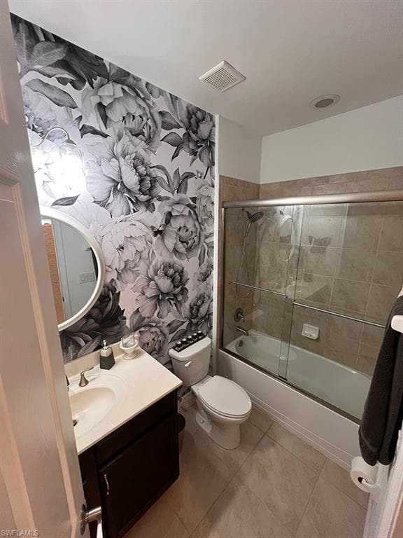 Bathroom with vanity, bath / shower combo with glass door, and light tile patterned floors