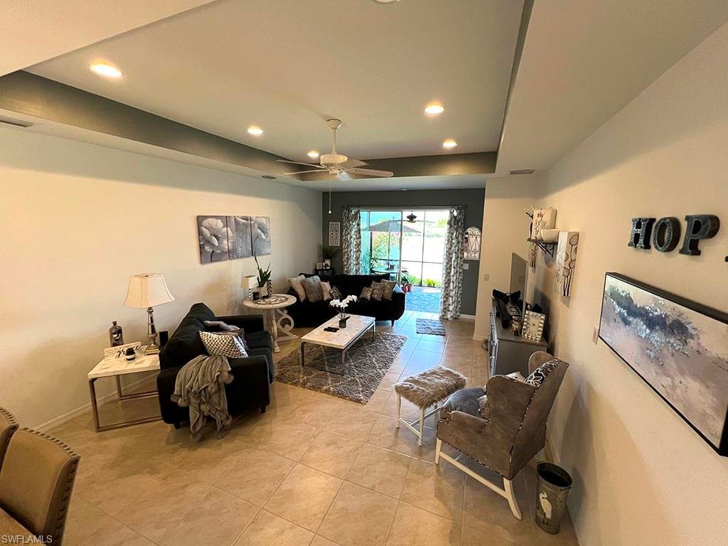Living area featuring a tray ceiling, a ceiling fan, recessed lighting, and light tile patterned floors