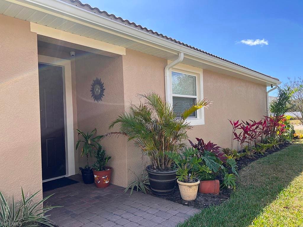 View of side of home with stucco siding, a patio, and a lawn