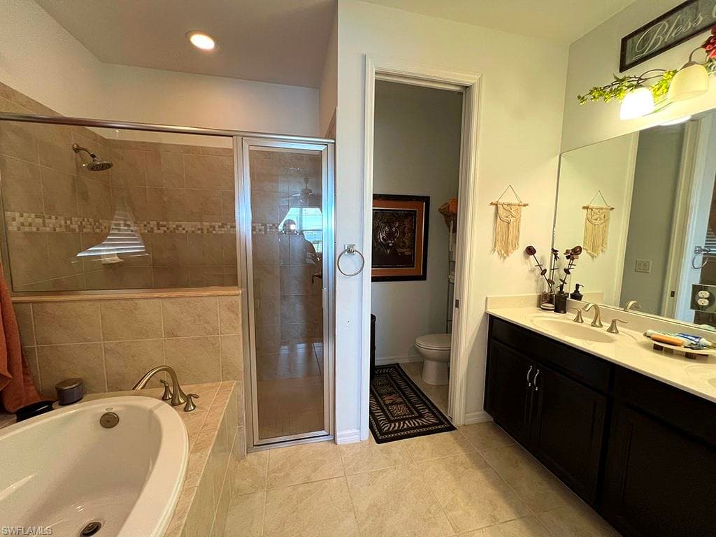 Bathroom featuring double vanity, a garden tub, a stall shower, and light tile patterned floors