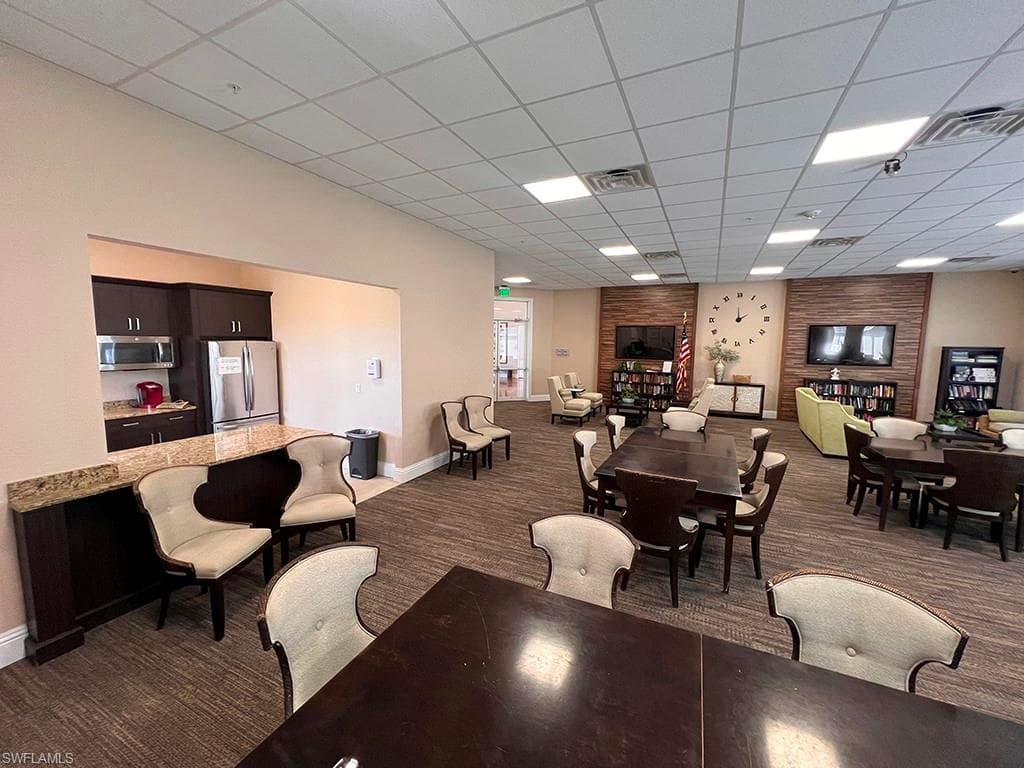 Dining room with a drop ceiling and dark colored carpet