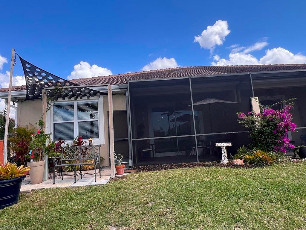 Back of property with a yard, a tile roof, a patio, and stucco siding