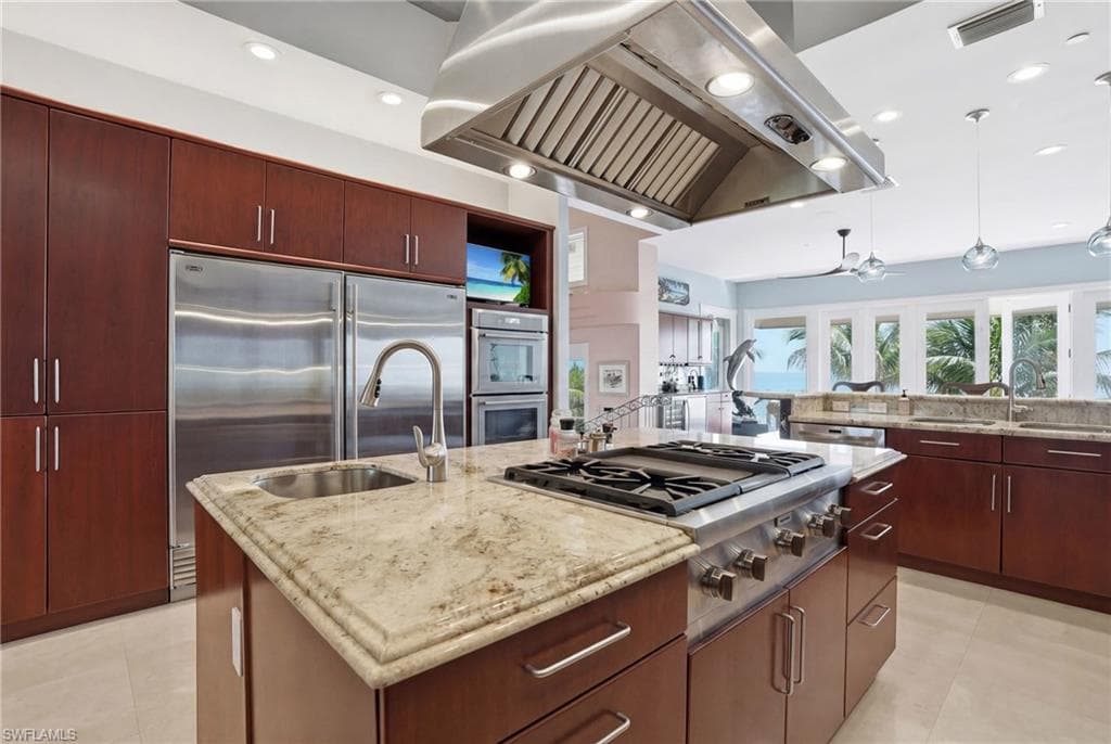 Chef’s kitchen with gas cooktop, prep sink, Thermador double ovens, Sub Zero refrigeration, custom cabinetry, and a statement stainless hood