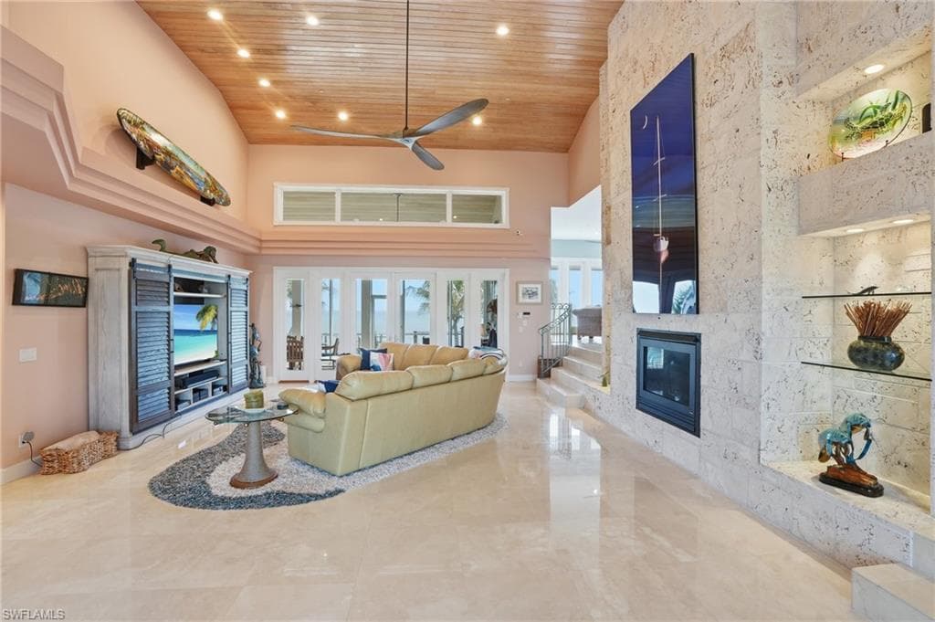 Living area featuring a high wooden ceiling, a fireplace, a ceiling fan, and recessed lighting