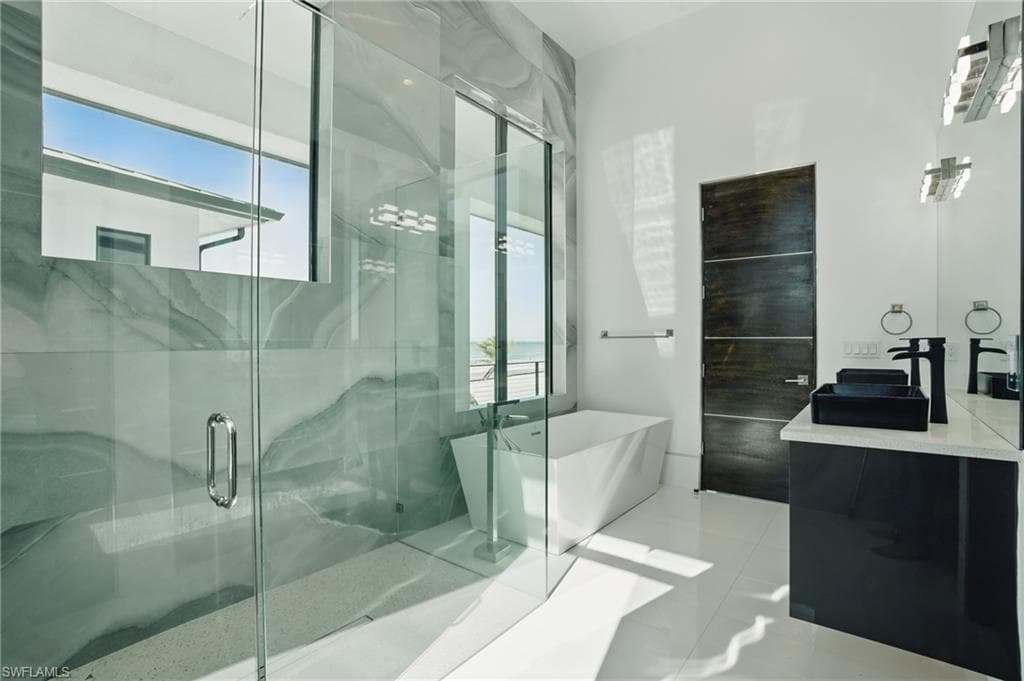 Full bathroom featuring vanity, a freestanding bath, plenty of natural light, and a marble finish shower Virtually Enhanced