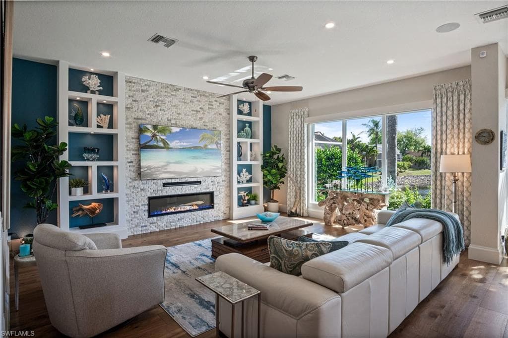 Picturesque living room is highlighted by a striking stone accent wall with fireplace & custom built-ins.
