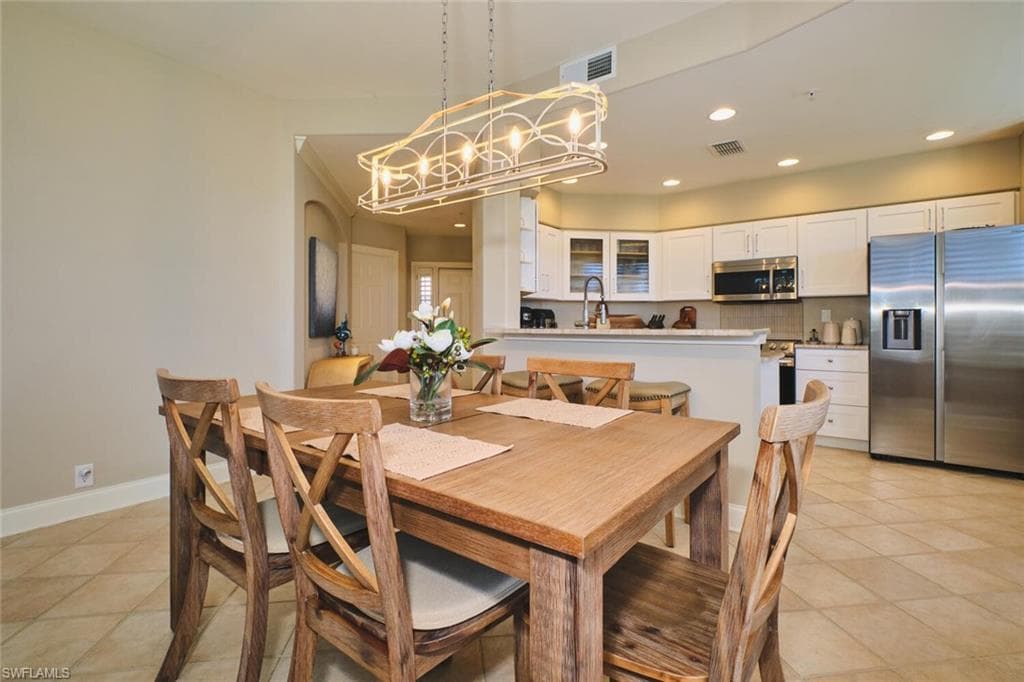 Dining space with light tile patterned floors and a chandelier