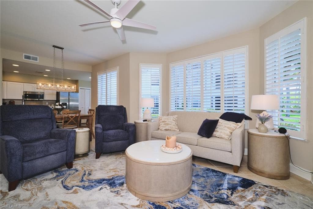Living room with a ceiling fan and light tile patterned flooring