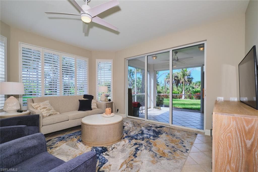 Living room featuring ceiling fan, light tile patterned floors, and healthy amount of natural light