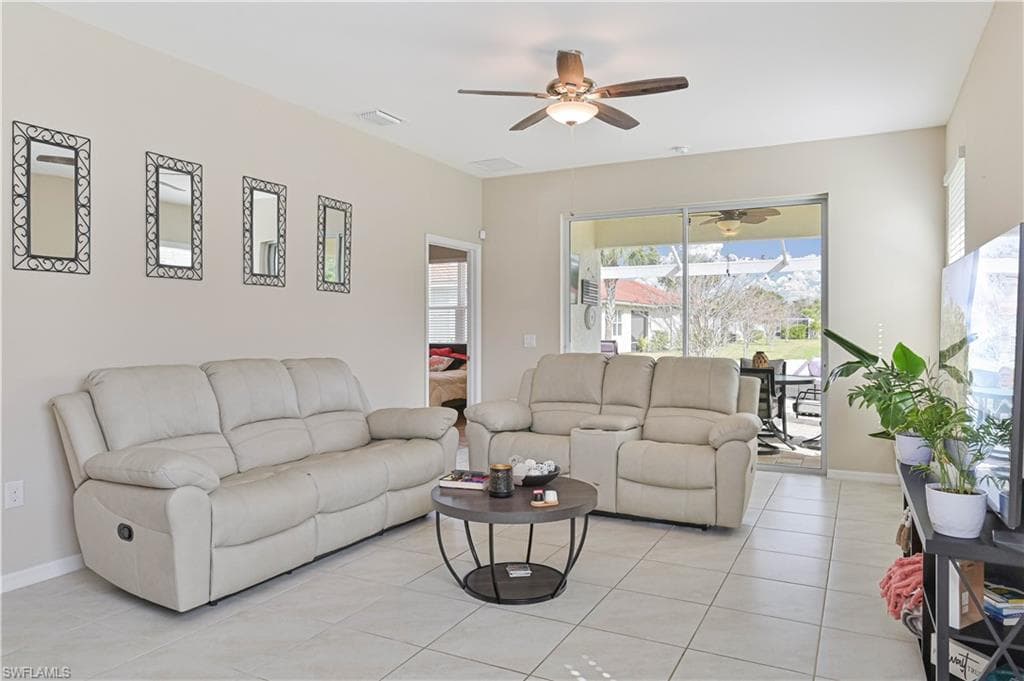 Living room with a ceiling fan and light tile patterned floors