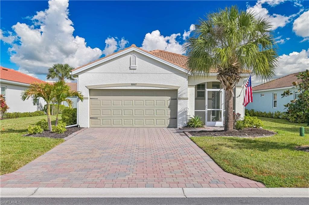 View of front of house with a front lawn, decorative driveway, a garage, and stucco siding