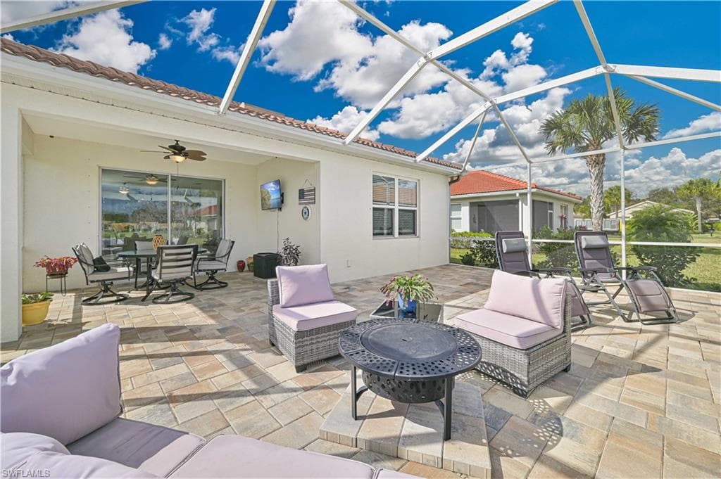 View of patio with a ceiling fan, a lanai, a sunroom, an outdoor living / dining area, and a fire pit