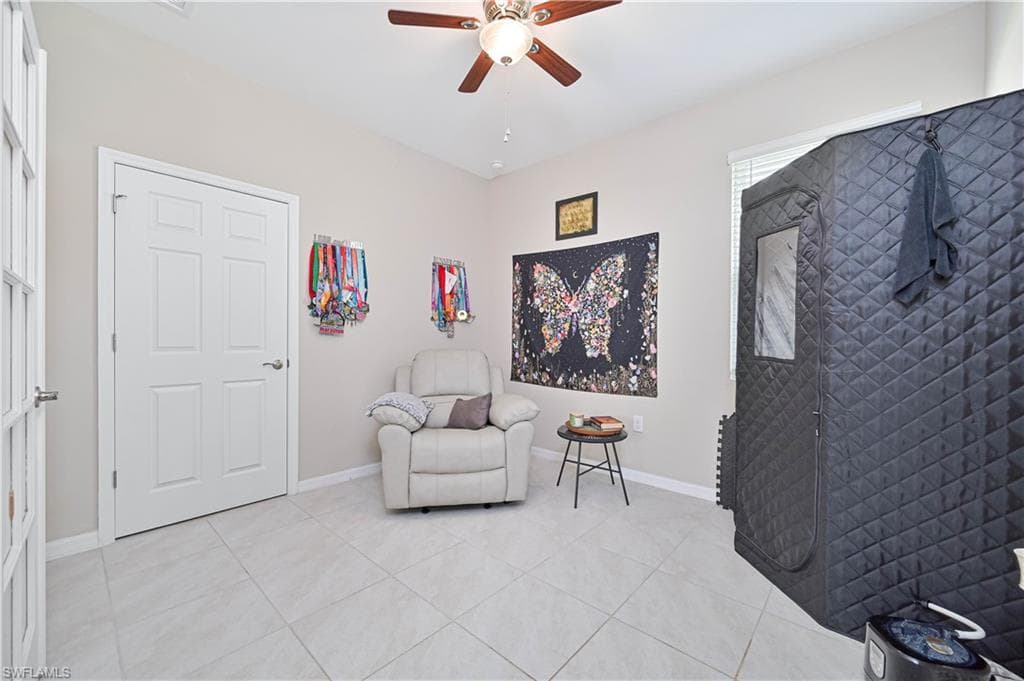 Sitting room with a ceiling fan and light tile patterned floors