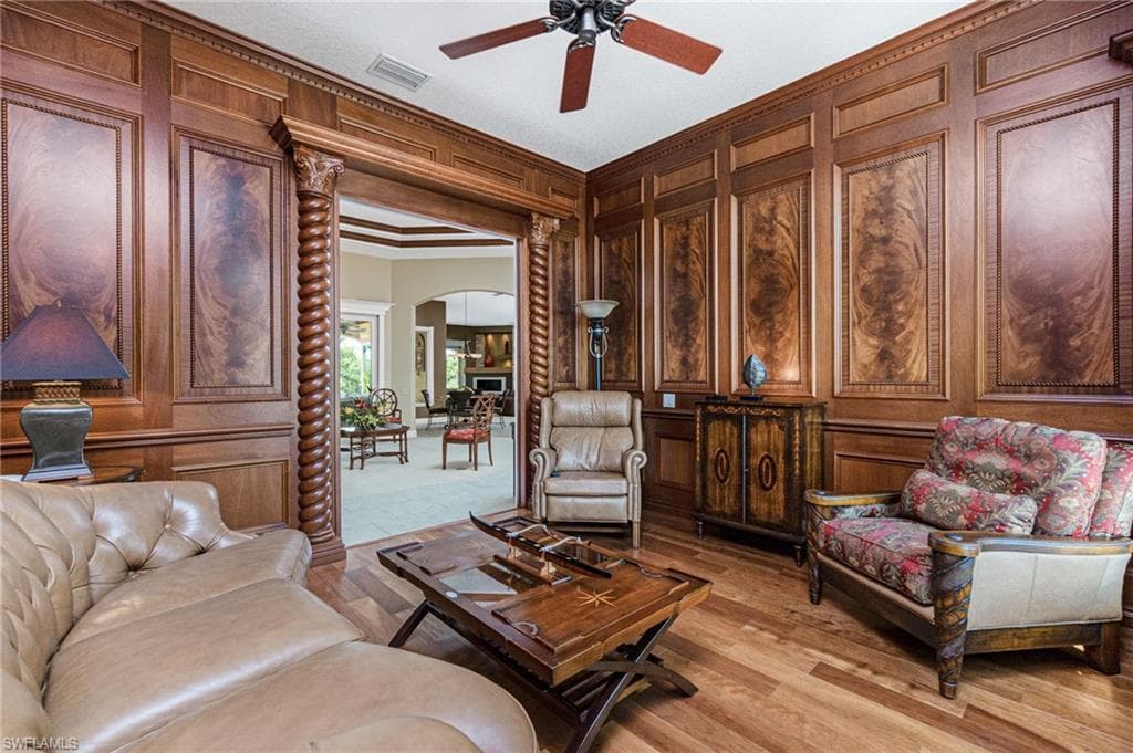 Sitting room with a decorative wall, arched walkways, crown molding, ceiling fan, and light wood-style floors