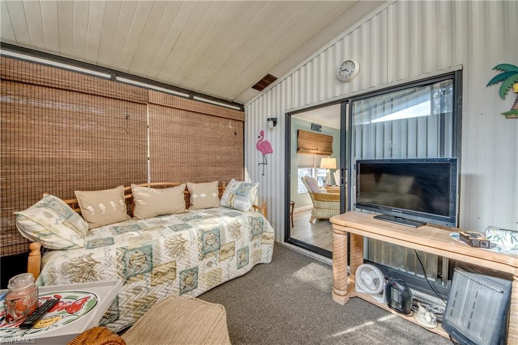 Carpeted living room with lofted ceiling and healthy amount of natural light
