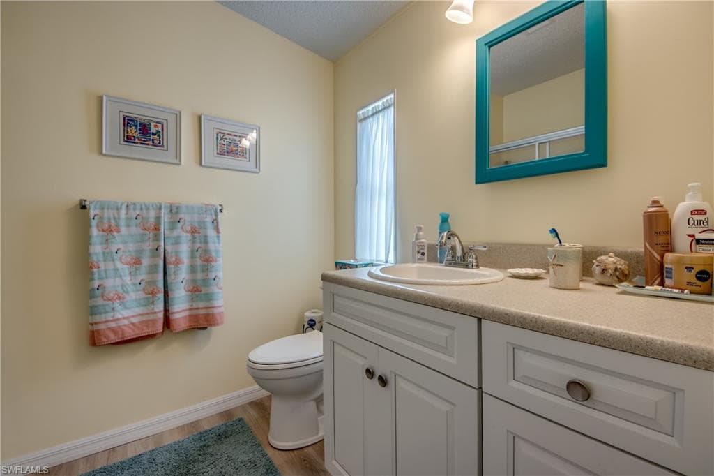 Bathroom with vanity, light wood-style flooring, and a textured ceiling