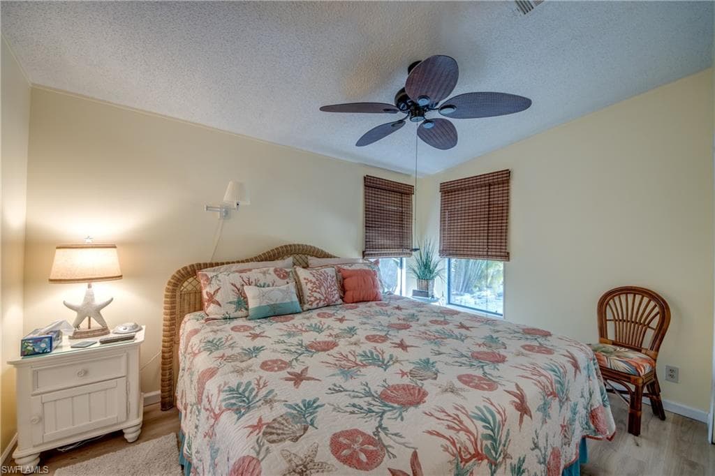 Bedroom featuring a textured ceiling, light wood-style floors, and a ceiling fan