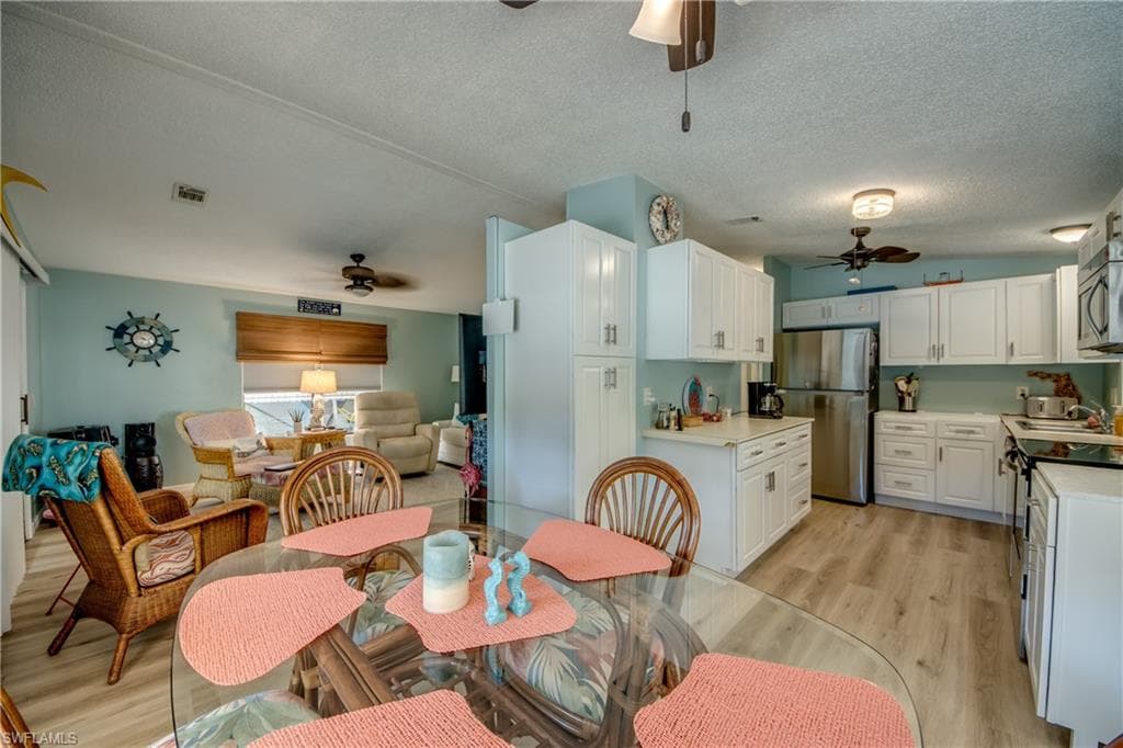 Dining room featuring ceiling fan, a textured ceiling, and light wood-type flooring