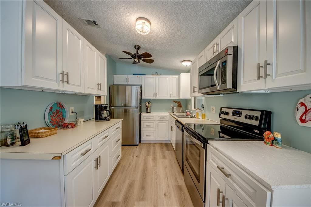 Kitchen featuring stainless steel appliances, white cabinetry, a ceiling fan, and light countertops