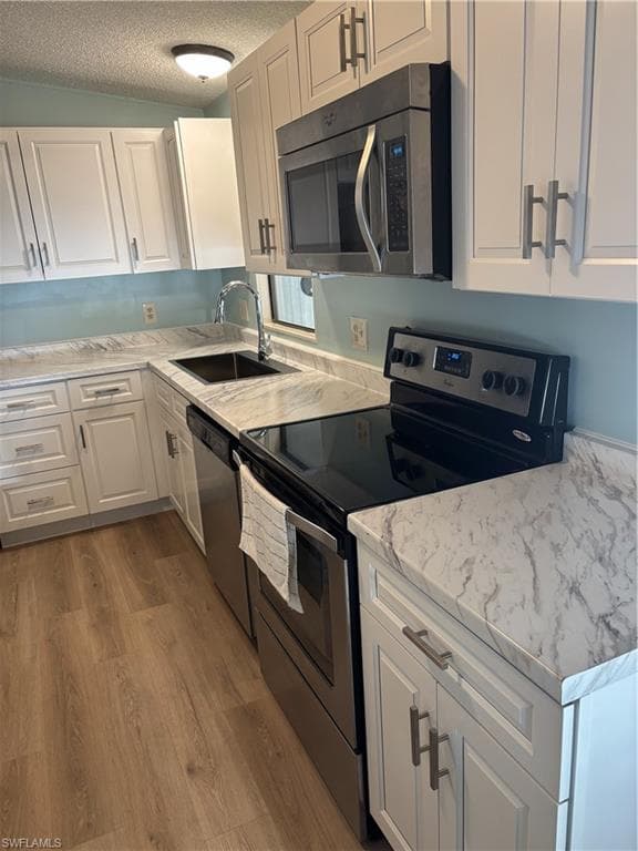 New Kitchen featuring white shaker-style cabinetry, a stainless steel over-the-range microwave, a stainless steel electric range, a stainless steel dishwasher, and wood-finish flooring