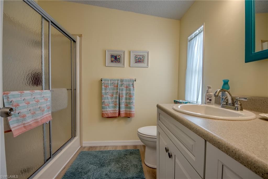 Full bathroom with a shower stall, vanity, light wood-style floors, and a textured ceiling