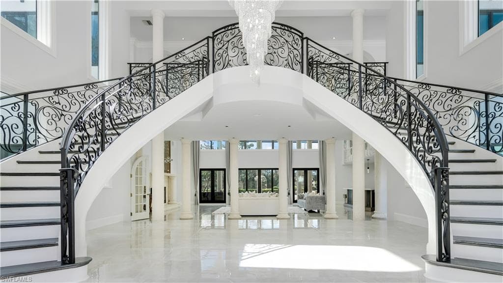Foyer featuring decorative columns, french doors, a high ceiling, and suspended lighting