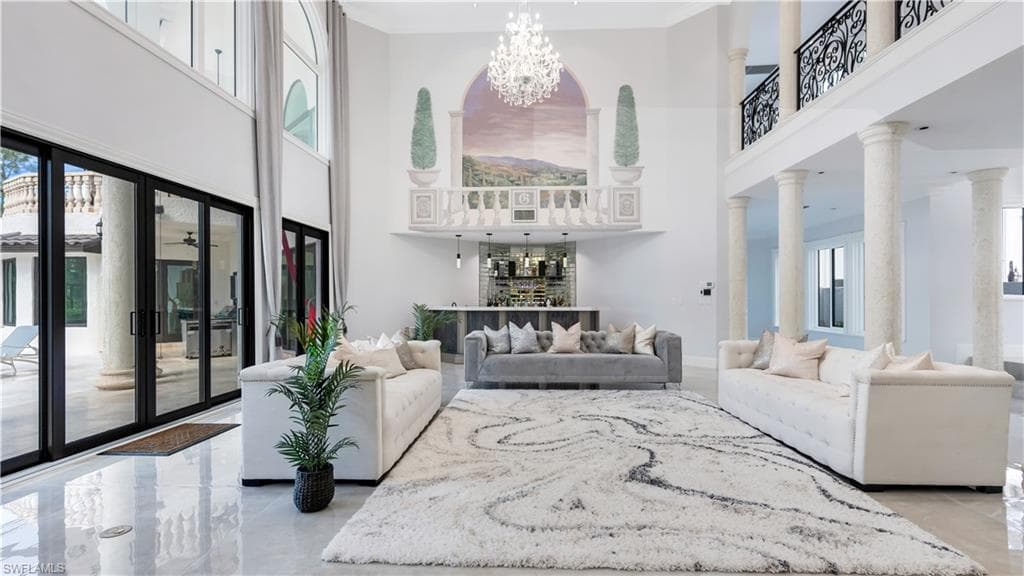 Living area with a chandelier, a high ceiling, ornamental molding, and ornate columns