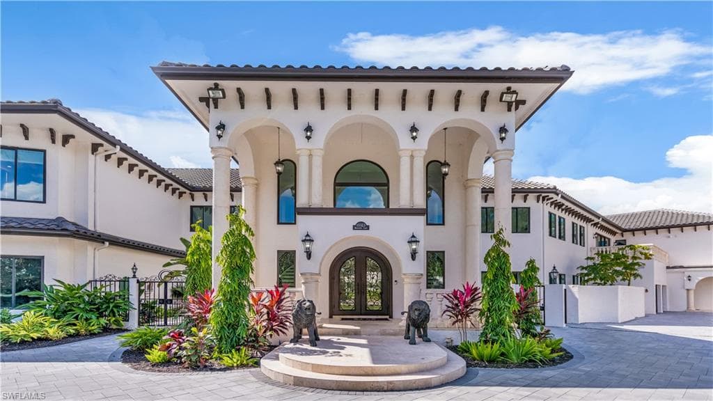 Mediterranean / spanish house with stucco siding, french doors, and driveway