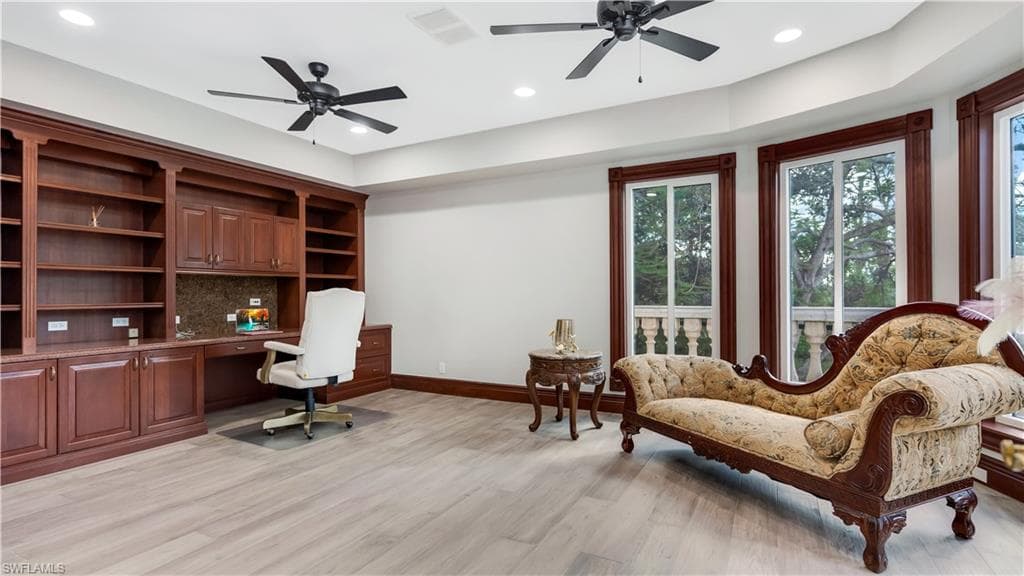 second office with built in study area, ceiling fan, light wood-style flooring, recessed lighting, and a tray ceiling