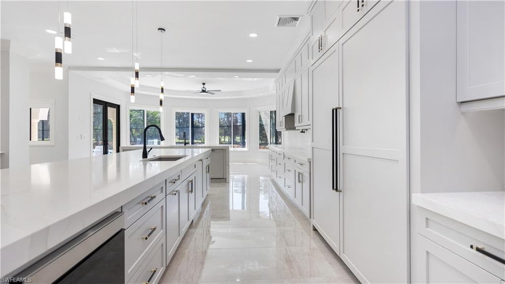 Kitchen featuring paneled built in fridge, light stone countertops, a ceiling fan, decorative light fixtures, and light marble finish flooring