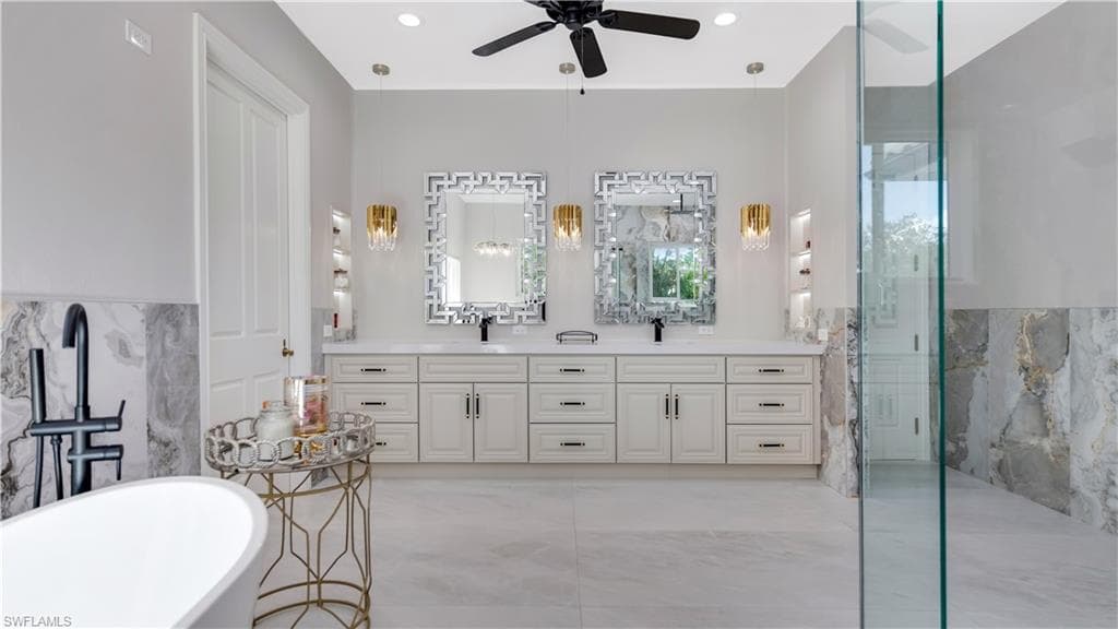 Bathroom with tile walls, double vanity, a soaking tub, a marble finish shower, and a wainscoted wall