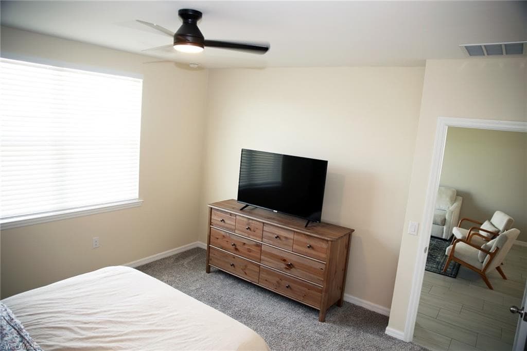 Carpeted bedroom featuring a ceiling fan and baseboards