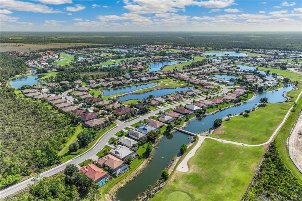 Aerial view showcasing a community with numerous properties, golf courses, and bodies of water