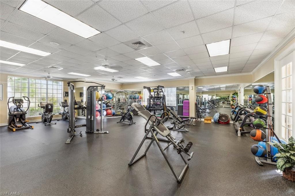 The property features an extensive fitness center with a variety of exercise equipment, large windows, and mirrored walls