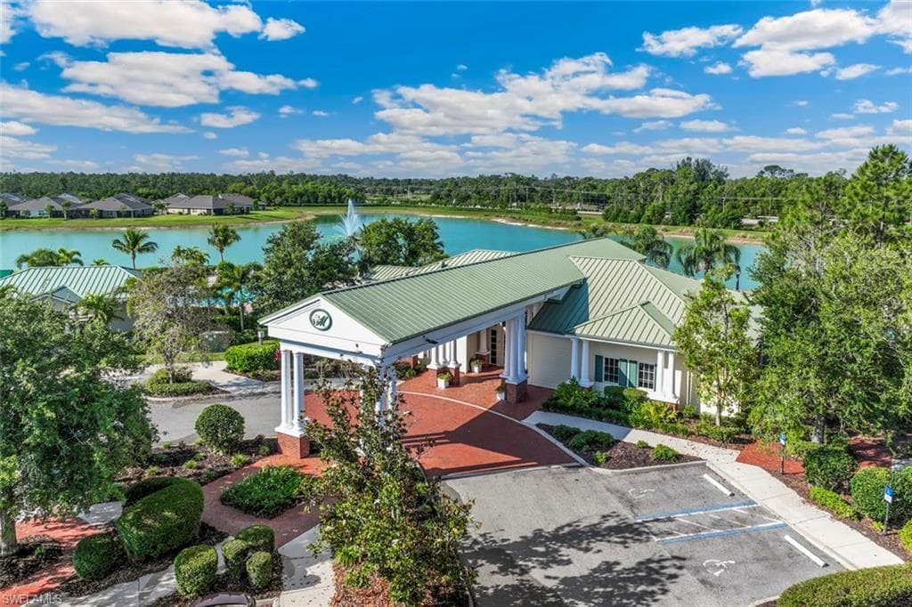 This property features a building with a green metal roof and a covered entryway, surrounded by lush landscaping