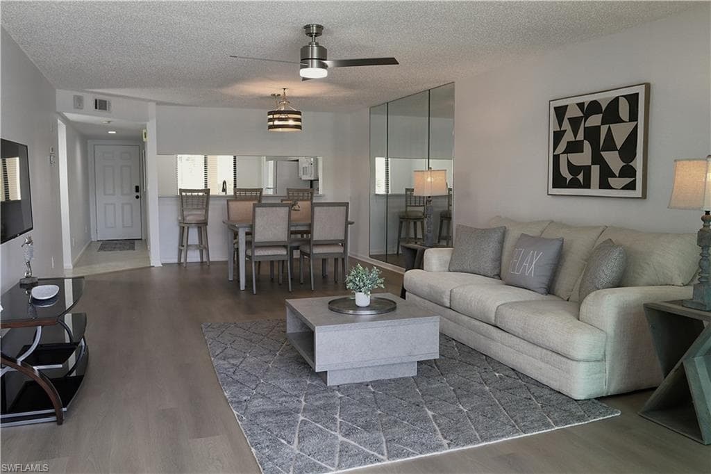 Living area with wood finished floors, a textured ceiling, and a ceiling fan