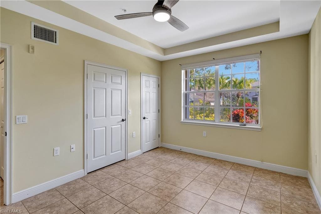Bedroom featuring a tray ceiling, ceiling fan, and light tile patterned floors
