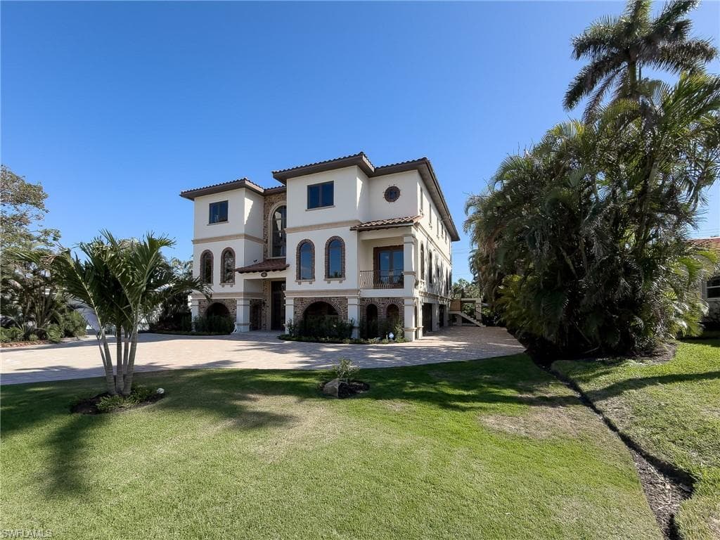 Mediterranean / spanish-style house with a balcony, stucco siding, a front yard, and a tile roof