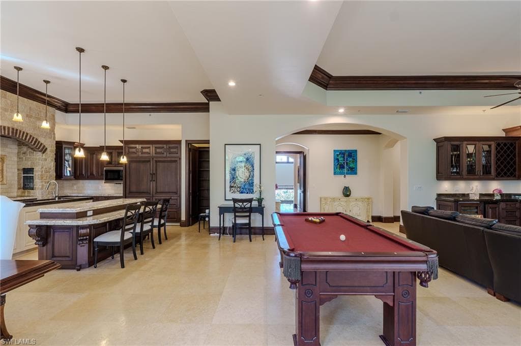 Rec room featuring arched walkways, ornamental molding, billiards table, bar with sink, and recessed lighting