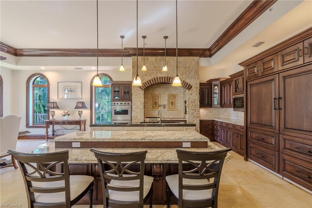 Kitchen featuring glass insert cabinets, dark stone countertops, crown molding, stainless steel appliances, and a tray ceiling