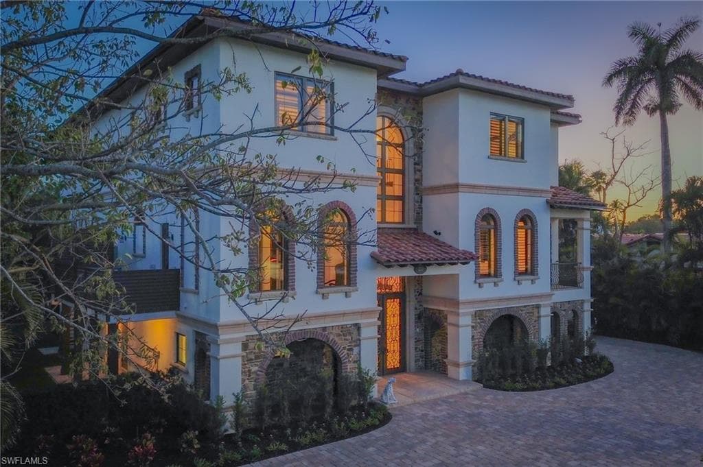 Mediterranean / spanish home featuring stone siding, stucco siding, decorative driveway, and a tile roof