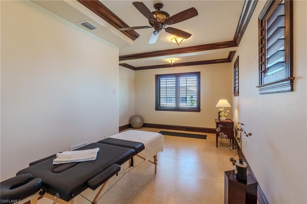 Exercise area with ornamental molding and ceiling fan